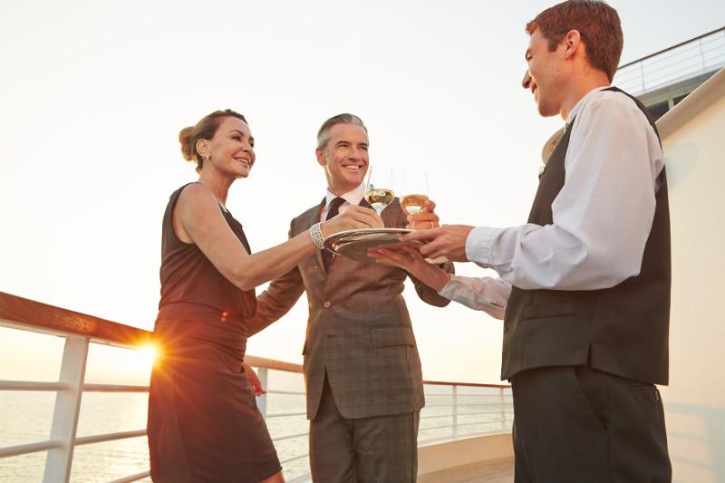 Couple is served drinks by a waiter on board luxury Seabourn cruise vessel